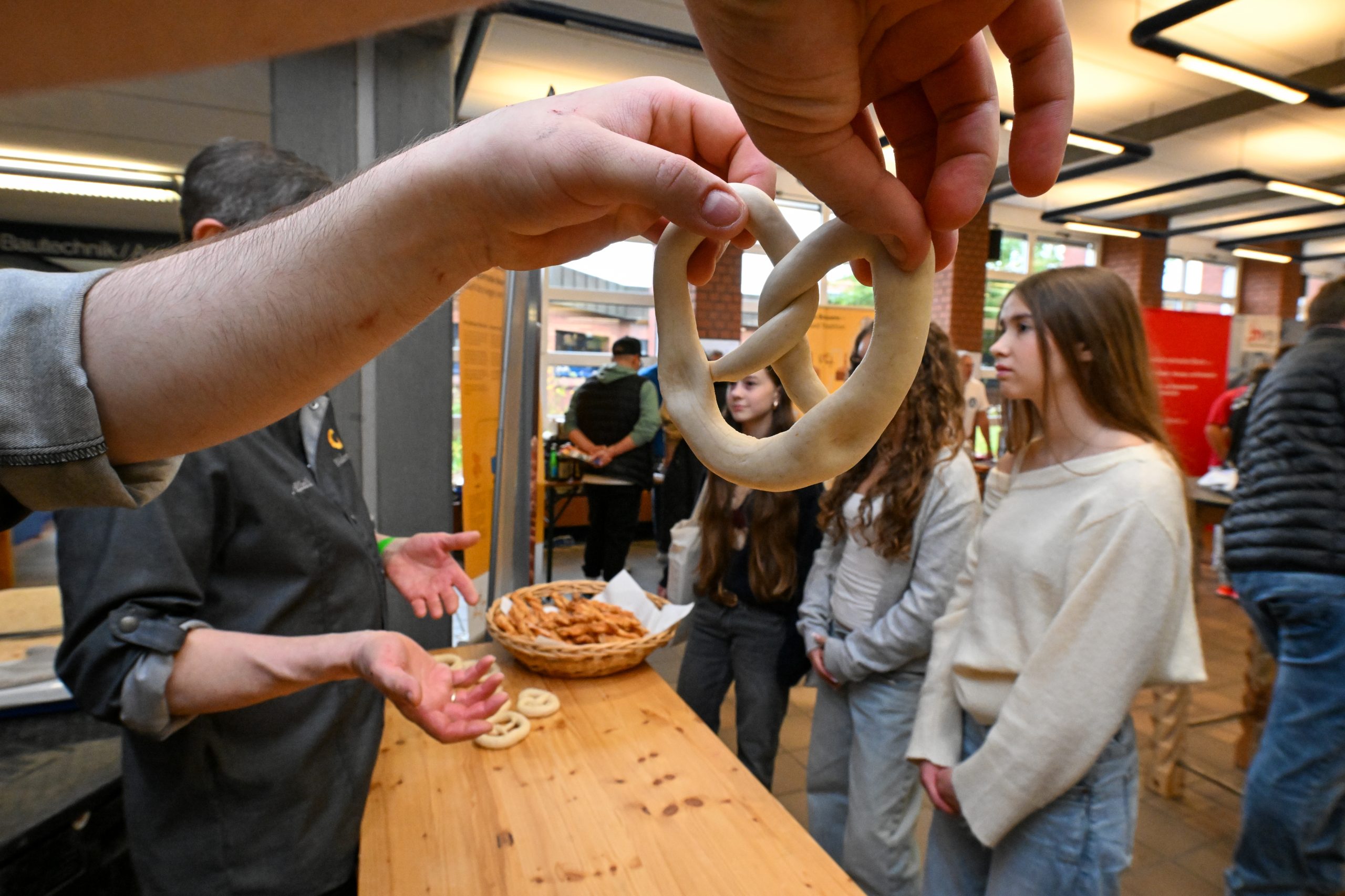 Jugendliche formen mit den Händen Teig zu Bretzeln.