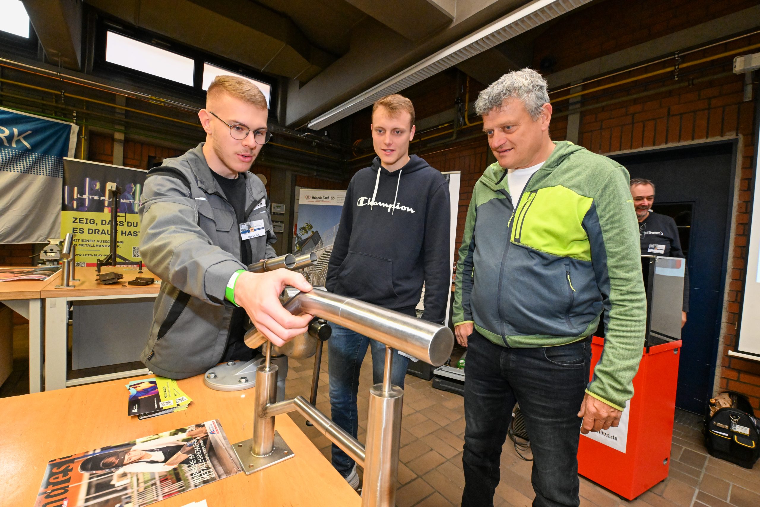 Ein Auszubildender setzt ein Geländer aus Metallrohren zusammen.