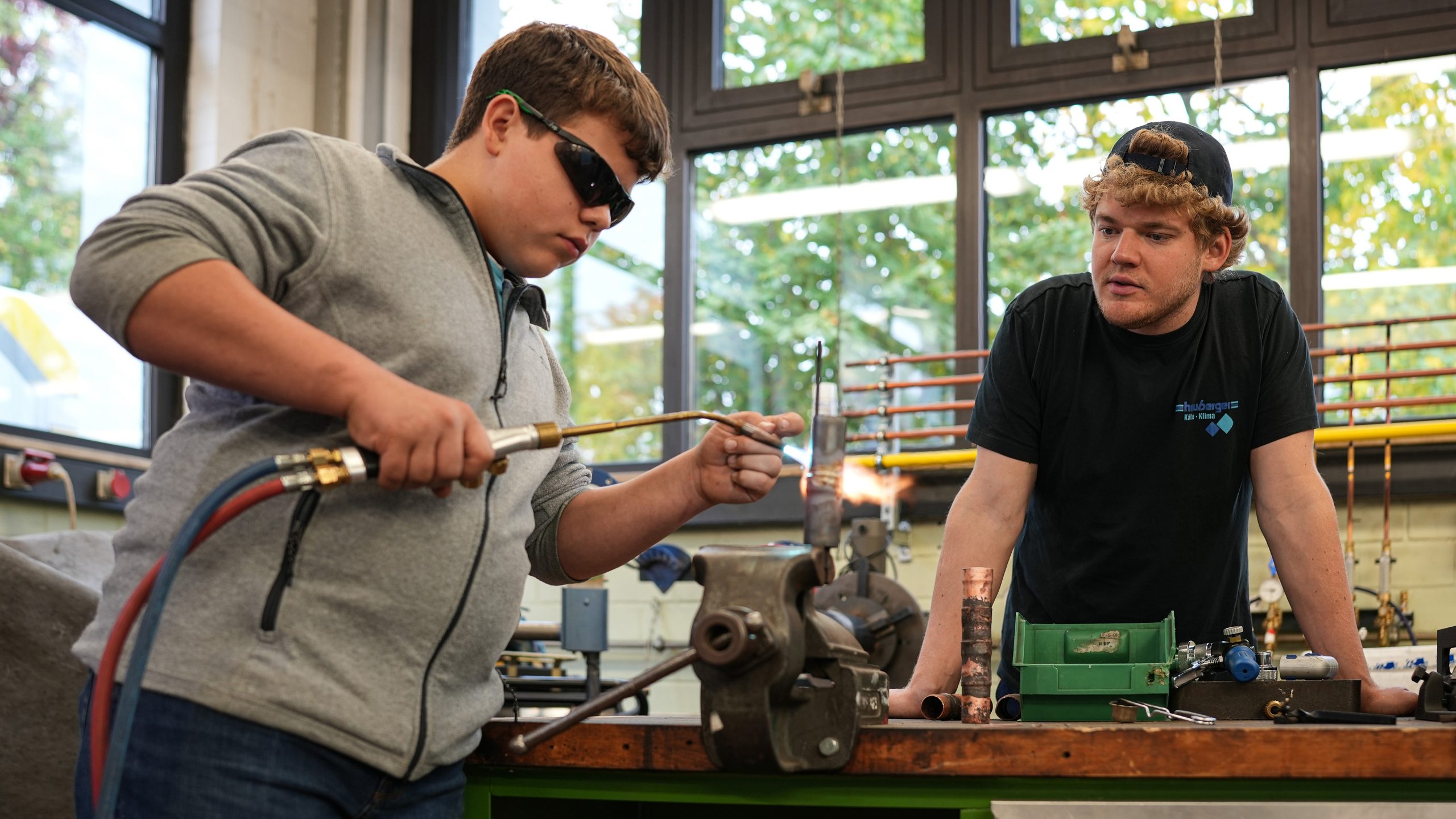 Ein Jugendlicher mit Schutzbrille schweißt zwei Metallrohre zusammen.