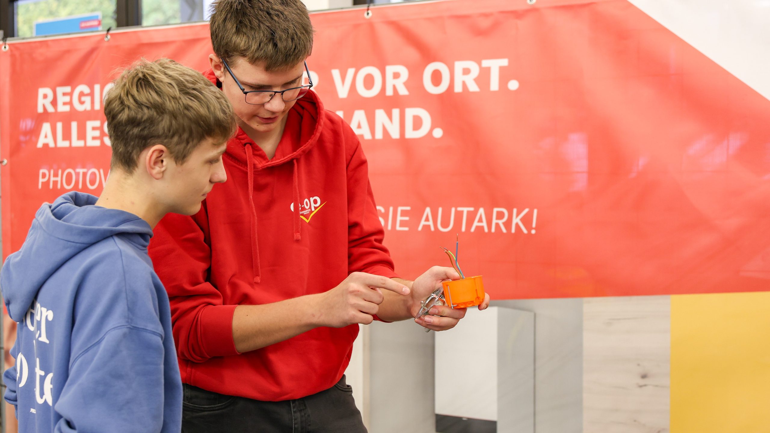 Ein Auszubildender zeigt einem Jugendlichen, wie ein Schaltkreis funktioniert.