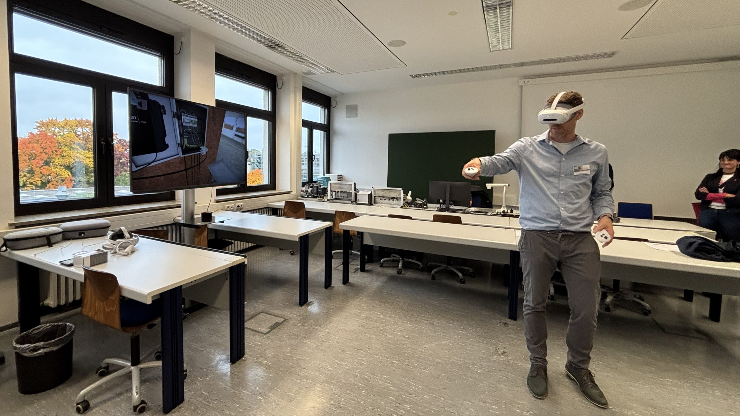 Ein Mann trägt eine VR-Brille und zeigt das Verkabeln eines Verteilerkastens am Bildschirm.